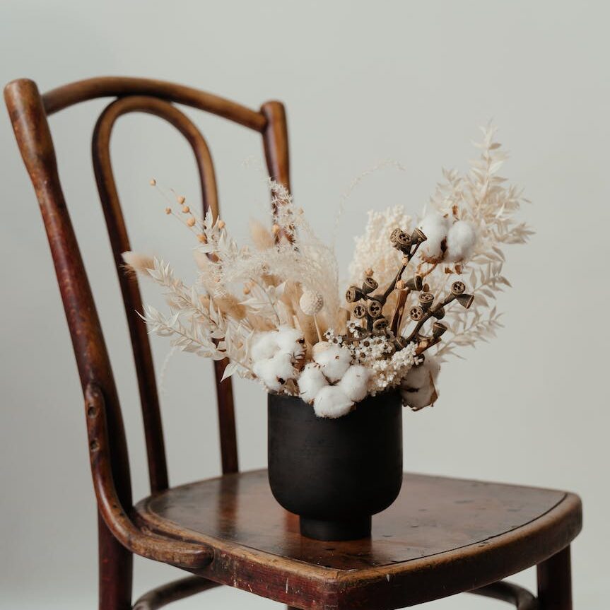 white flowers in black ceramic vase on brown wooden table